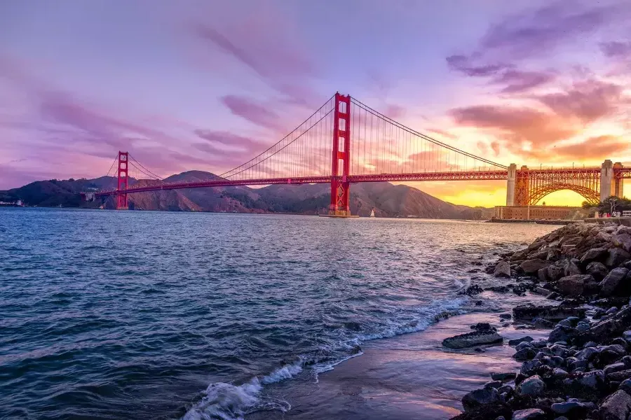 The 金门大桥 at sunset with a multicolored sky and the 贝博体彩app Bay in the foreground.